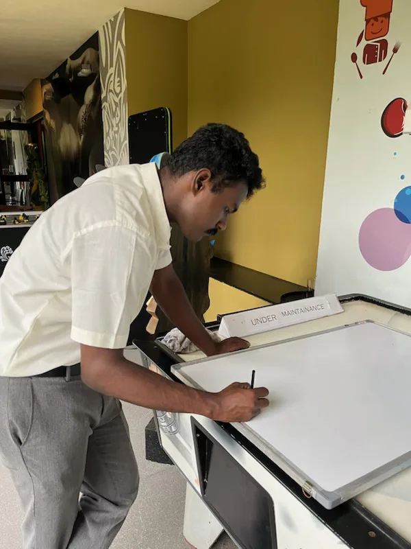 Naveen bent over an under-maintenance game table in Coorg, sketching on a whiteboard during the Club Mahindra years.