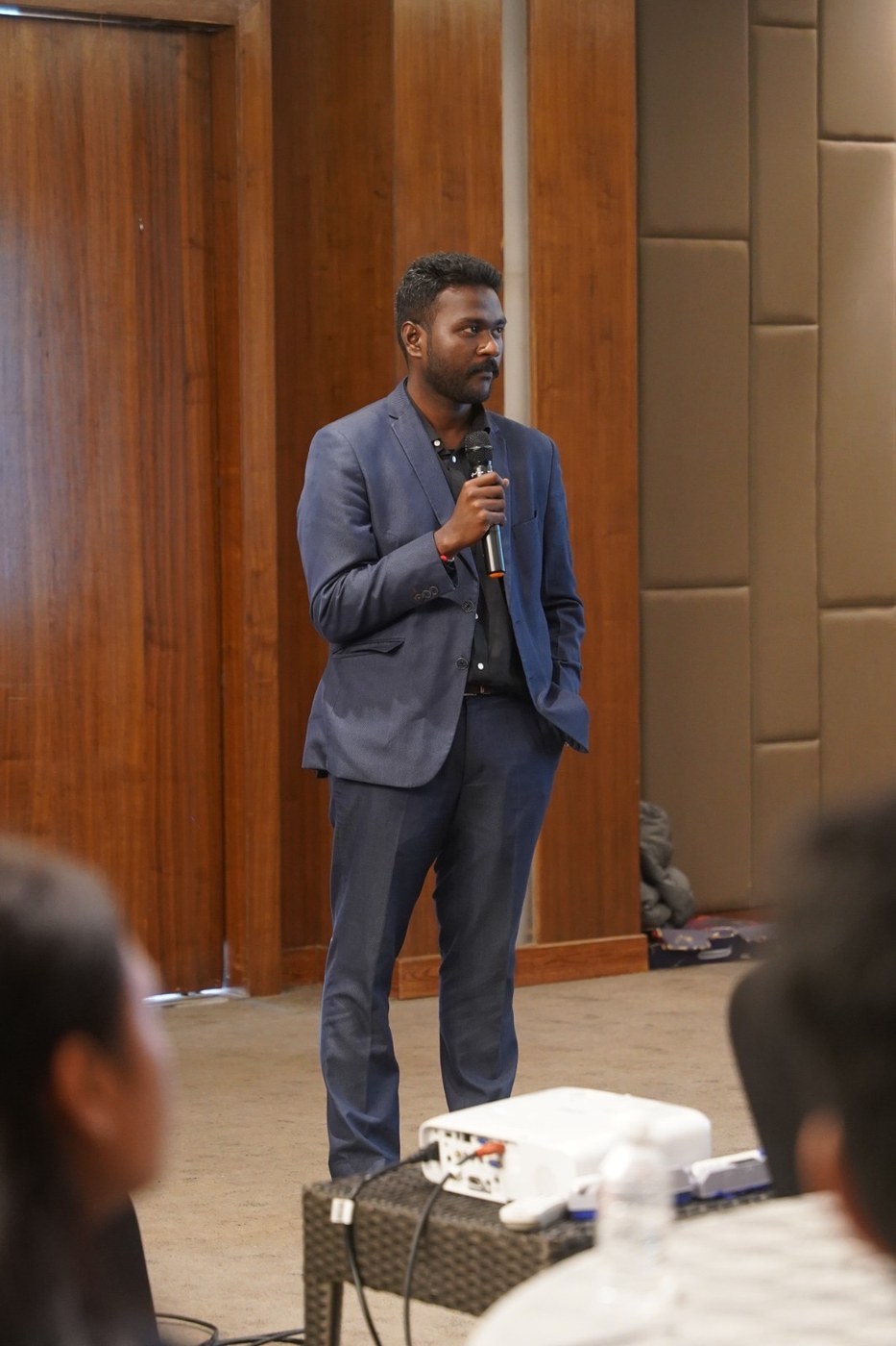 Naveen speaking to an audience with a projector visible in the foreground at Courtyard by Marriott, Mahabaleshwar.