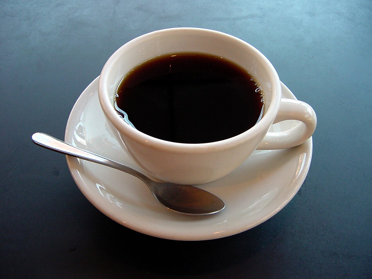 A hot cup of tea on a table, with visible warmth spreading into the cooler room.