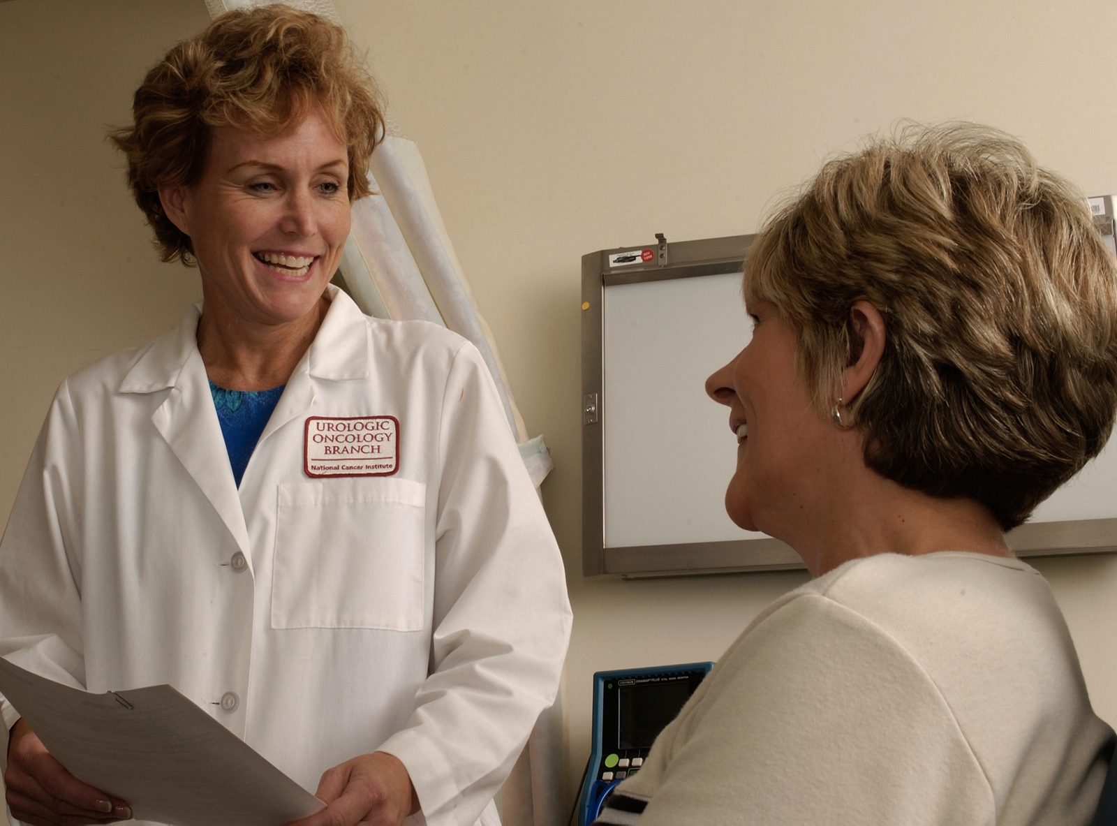 A doctor sitting with a patient during a consultation, both engaged in conversation.