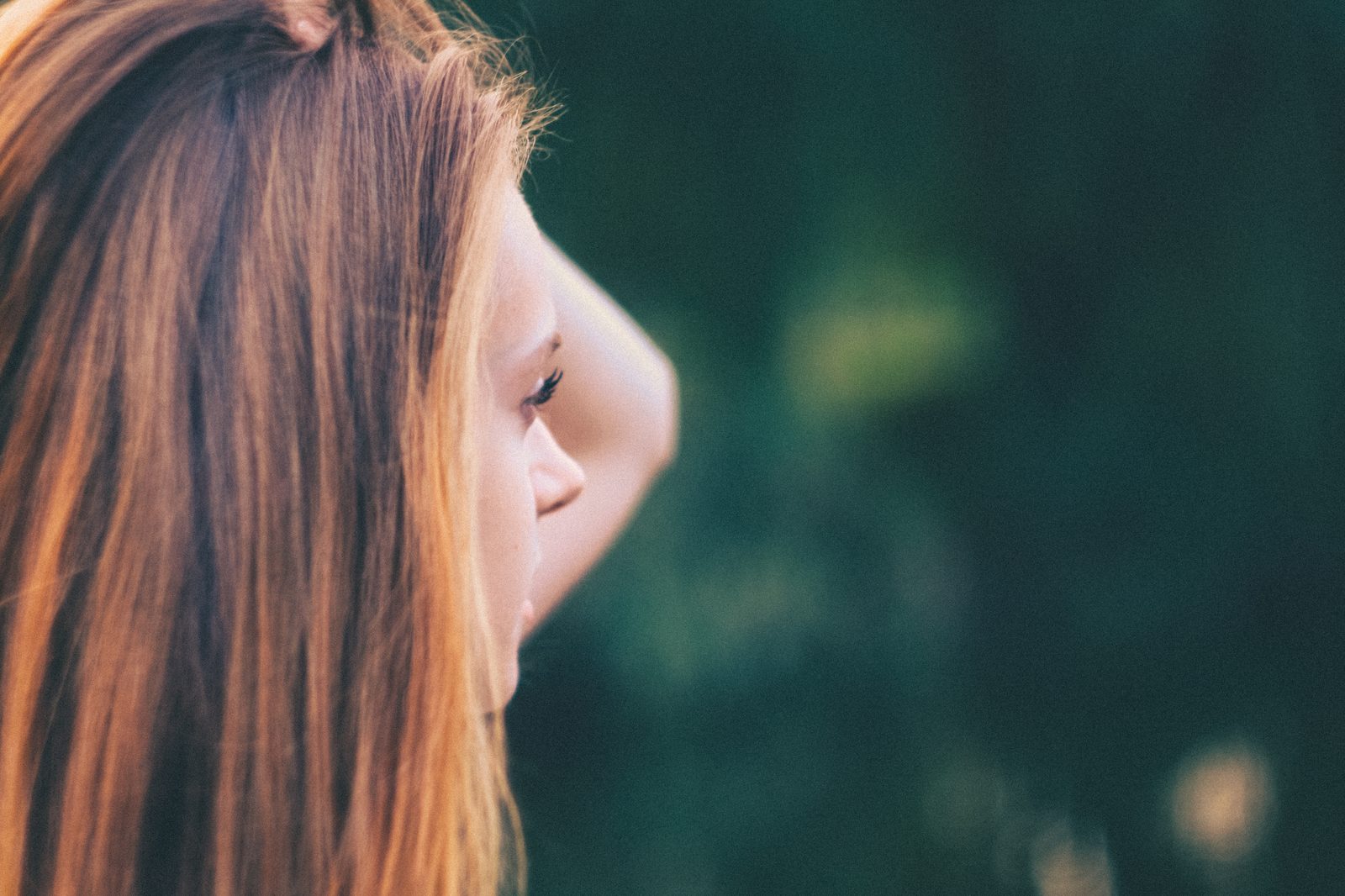 A woman outdoors looking off into the distance rather than toward the camera.