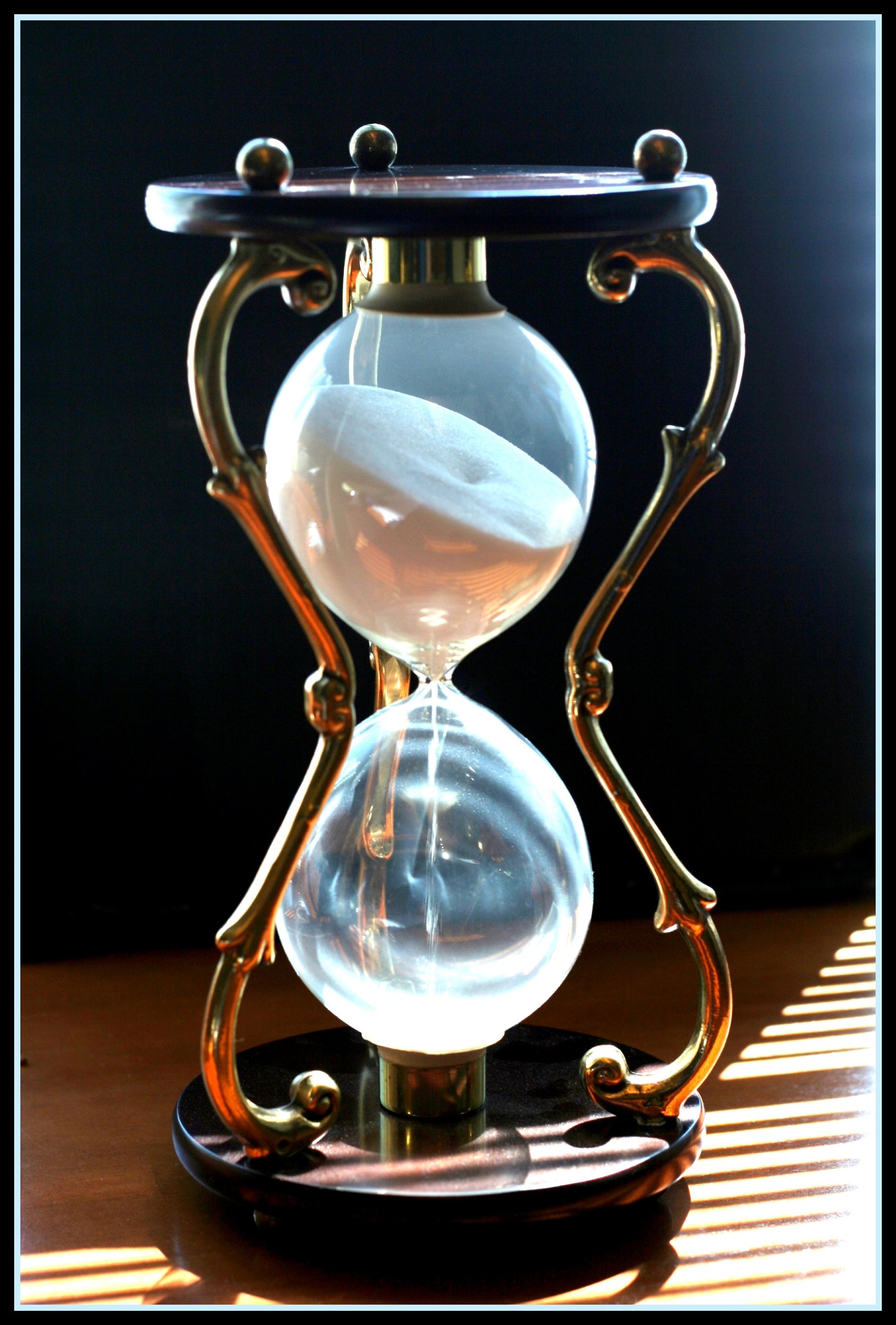 An hourglass with sand flowing unevenly between chambers